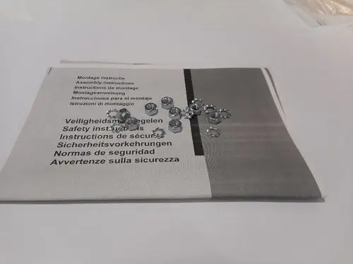 Ersatzteile von Remeha, bestehend aus mehreren silbernen Schrauben unter Montageanleitungen in mehreren Sprachen, die auf einem weißen Untergrund liegen.